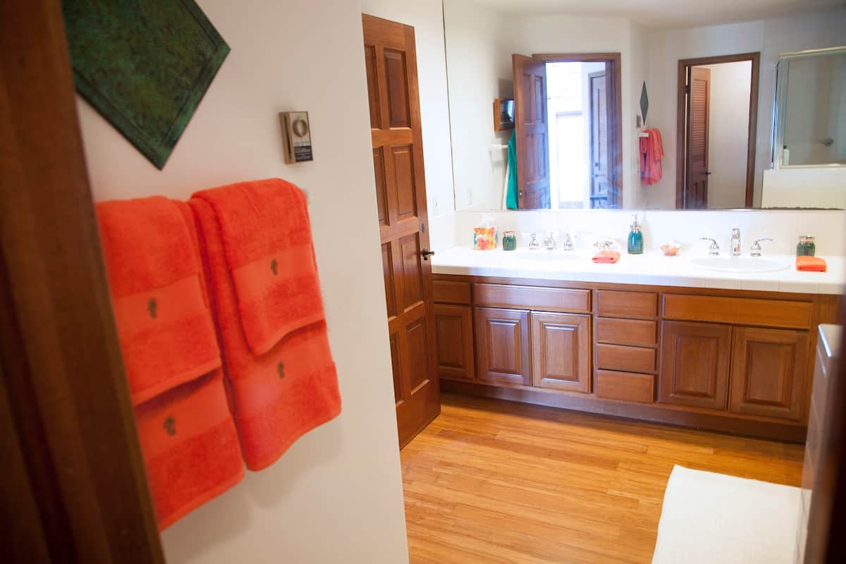 Bathroom vanity with wood cabinets and red towels