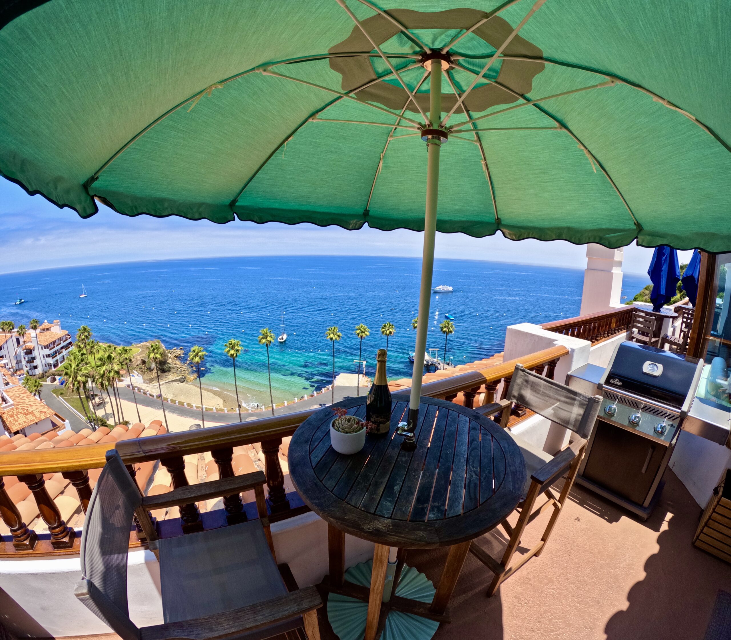Balcony dining table with green umbrella and ocean view