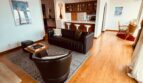 Living room with leather sofa and armchair, open to the kitchen
