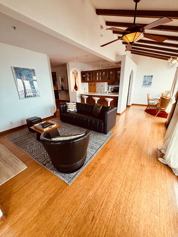 Living room with leather sofa and armchair, open to the kitchen