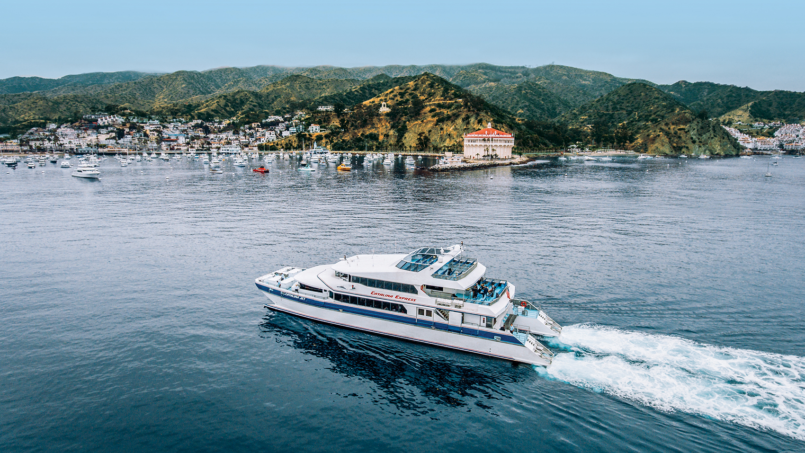 A Catalina Express ferry crossing toward Avalon, with the town and the island hills behind it.